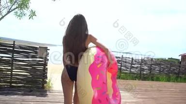 在阳光明媚的日子里，比基尼女孩带着洒满甜甜圈在游泳池里漂浮。 派对，酒店，海滩，度假，度假，旅行